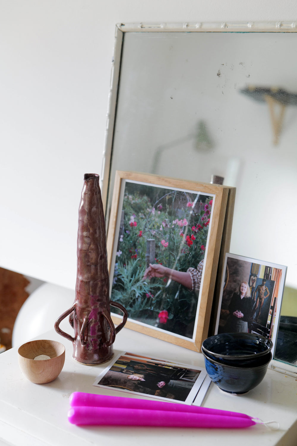 A vase, bowls, postcards and candles arranged on a table.