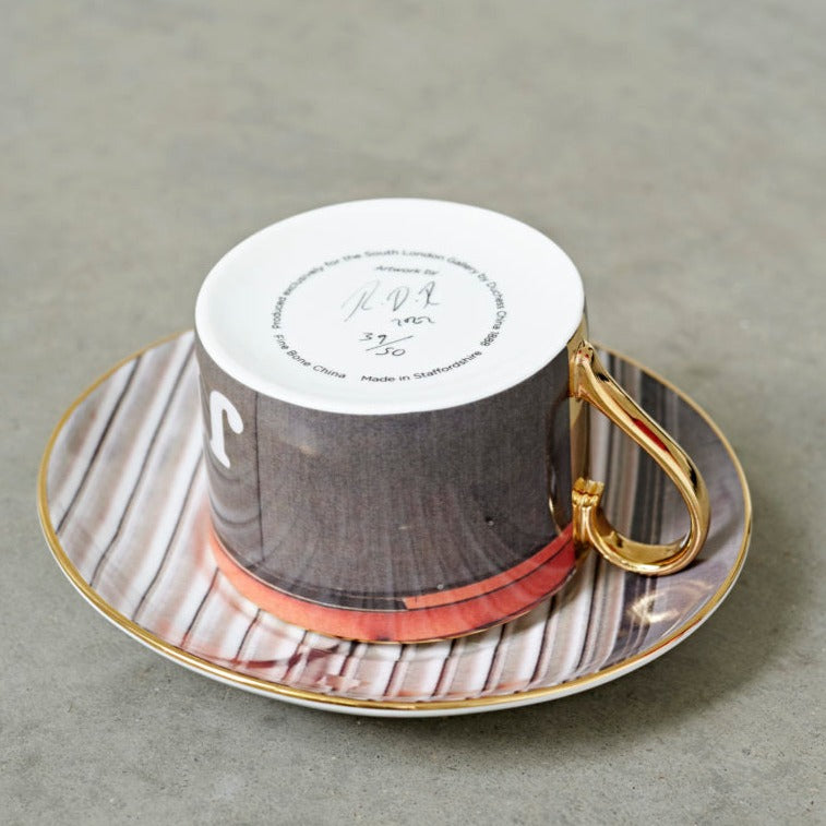 A teacup and saucer by the artist Rene Matic. The teacup is placed upside down on the saucer.