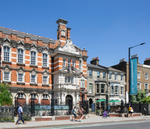 A Victorian building with a blue banner with South London Gallery printed on it. The sky is blue.