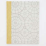 A book titled The Orozco Garden at the South London Gallery. The cover of the book is grey with a yellow spine. There are geometric patterns and circles underneath the text on the front.