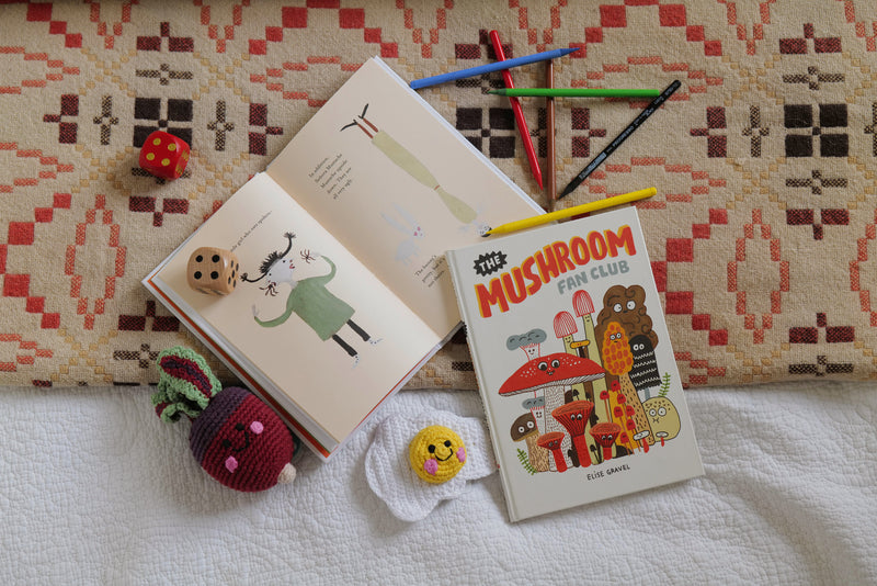 Children's books, toys and pencils laid out on a bedspread.