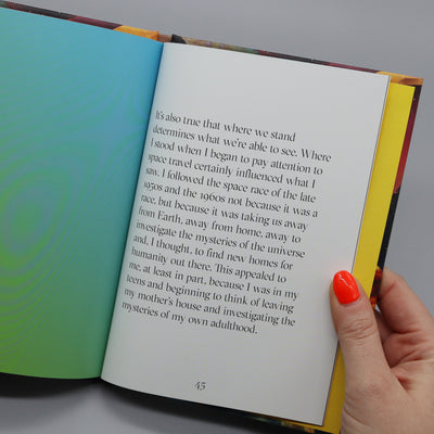 Inside pages of a book. The book is being held open by a hand.