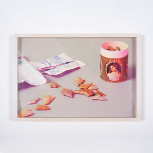 A limited edition print of a film still featuring notes of money and a pot with a portrait of a woman on the side.