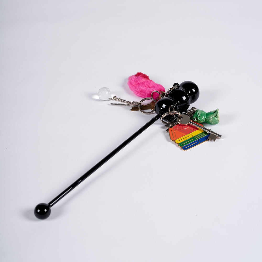 A black stirrer with keychains attached to it.