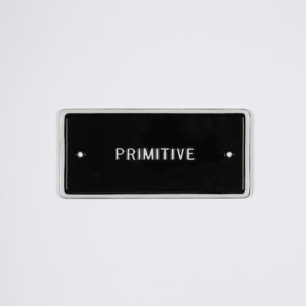Black sign with the word Primitive written on it. This is a limited edition artwork by artist Peter Liversidge