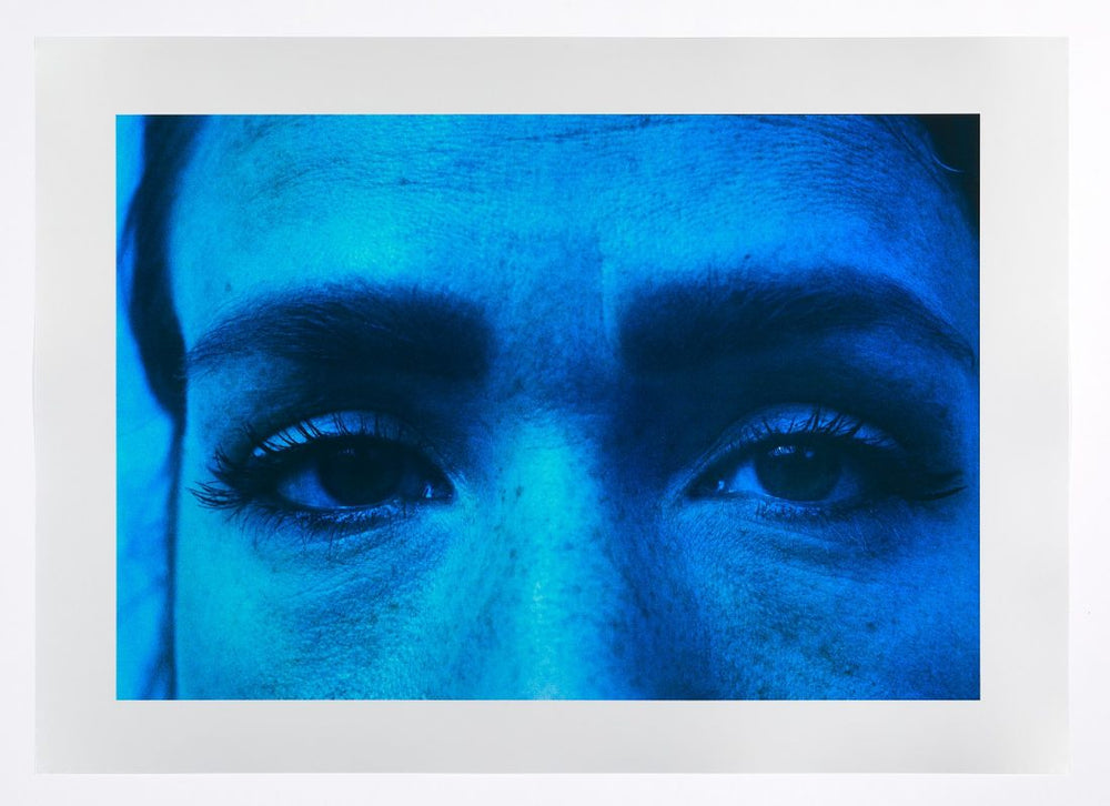 A bright blue photograph of a persons eyes and eyebrows by artist Basim Magdy