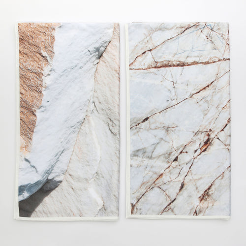 Two beach towels lying beside each other. The images on the towels are close up photos of rocks. These were made by artist duo Something and Son and are exclusive to the South London Gallery