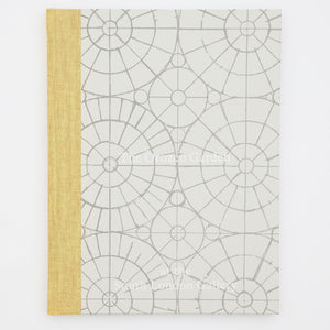 A book titled The Orozco Garden at the South London Gallery. The cover of the book is grey with a yellow spine. There are geometric patterns and circles underneath the text on the front.